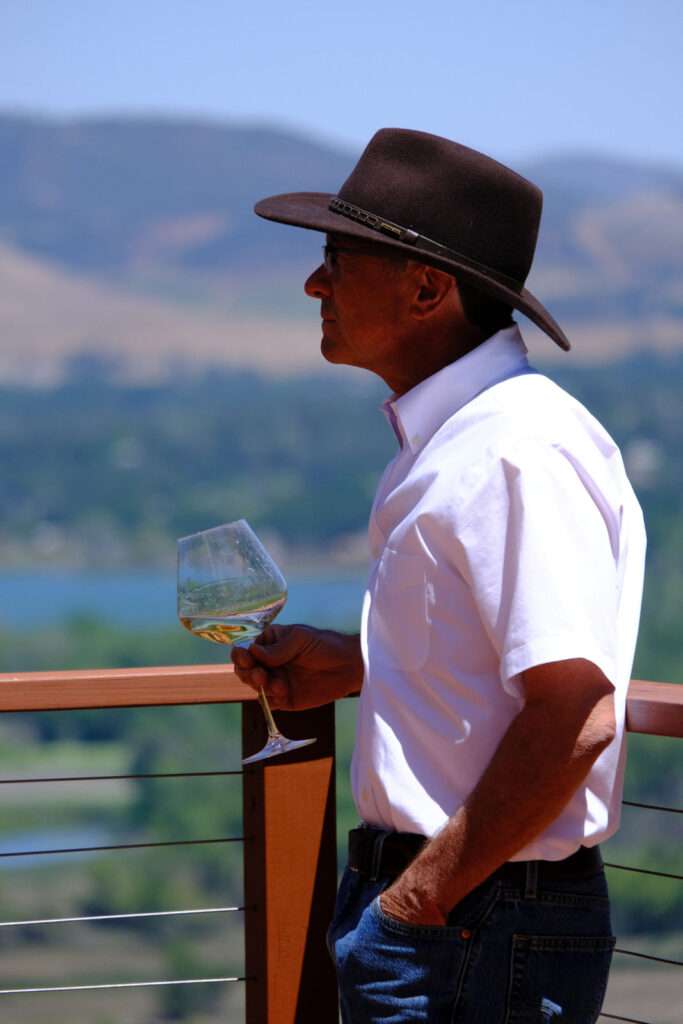 a man wearing a hat and holding a wine glass.